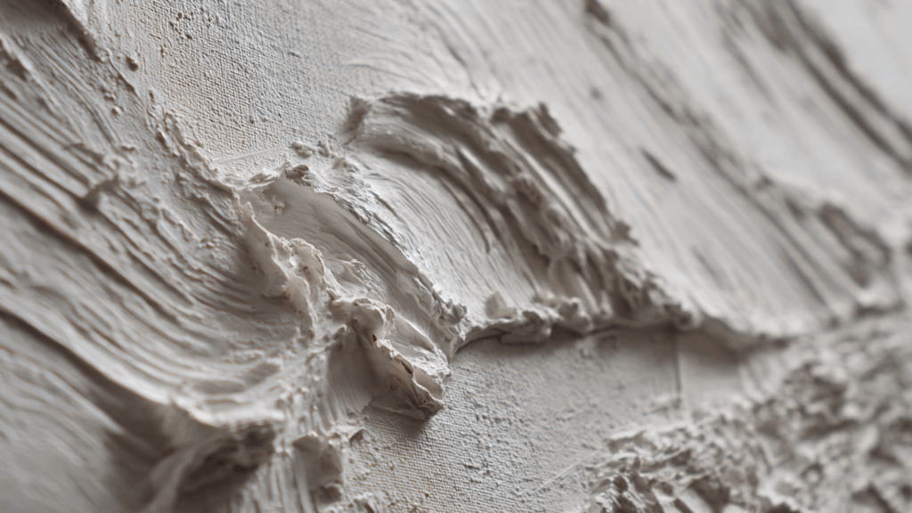 A close-up detail shot of wet joint compound texture on a canvas, showing sculptural arches and lines.